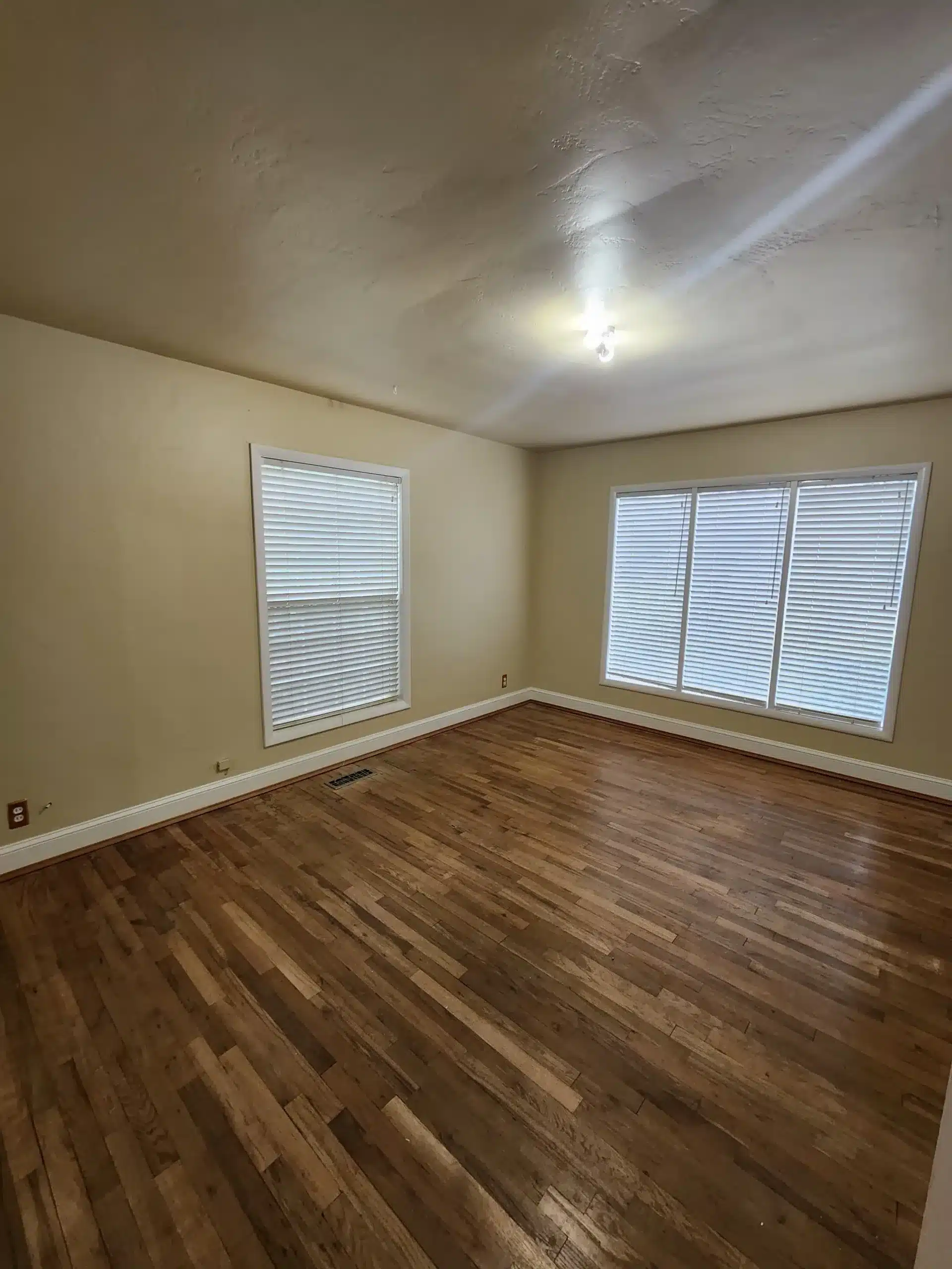 Interior residential painting Empty room with freshly painted tan walls, white baseboards, and hardwood floors