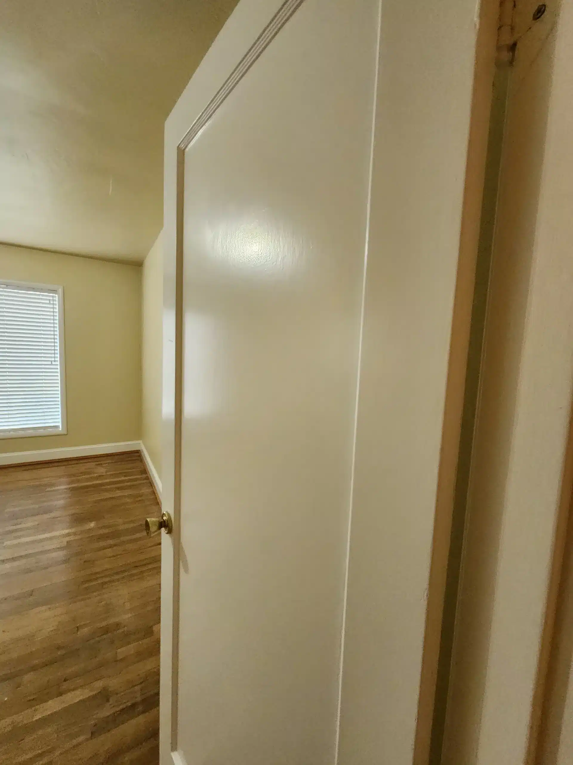 Interior residential painting Freshly painted white interior door opening to a bedroom with yellow walls and hardwood floors