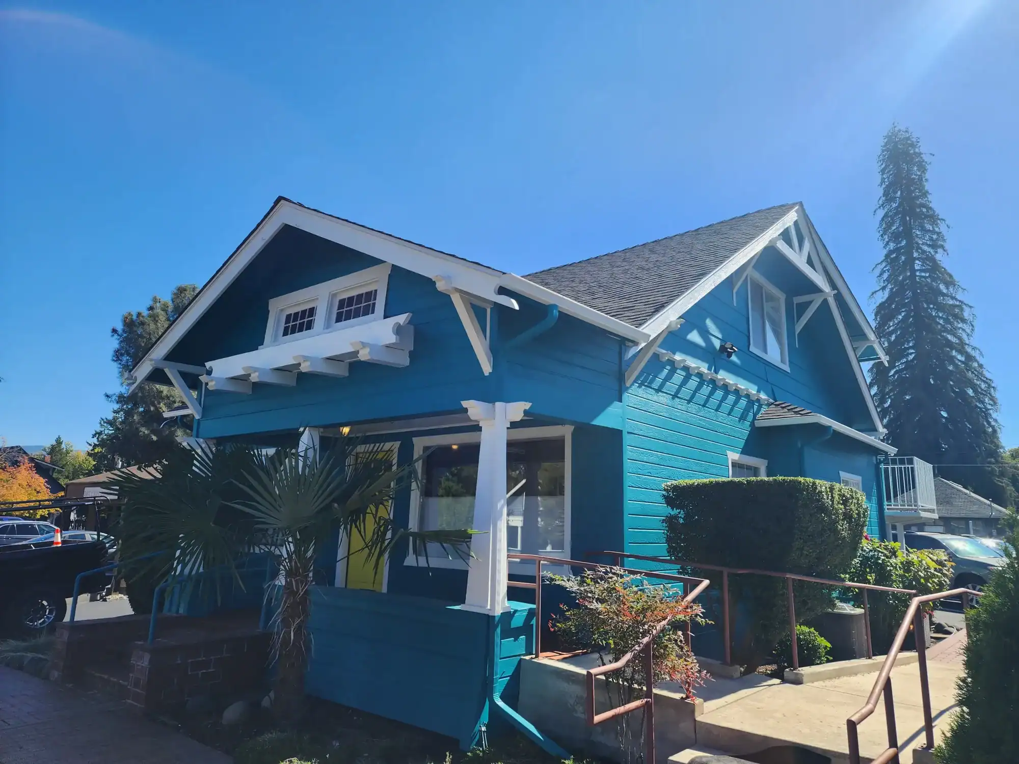 20231004_134140 Historic craftsman bungalow freshly painted in bold teal with white trim, exposed rafter tails, and decorative gable brackets