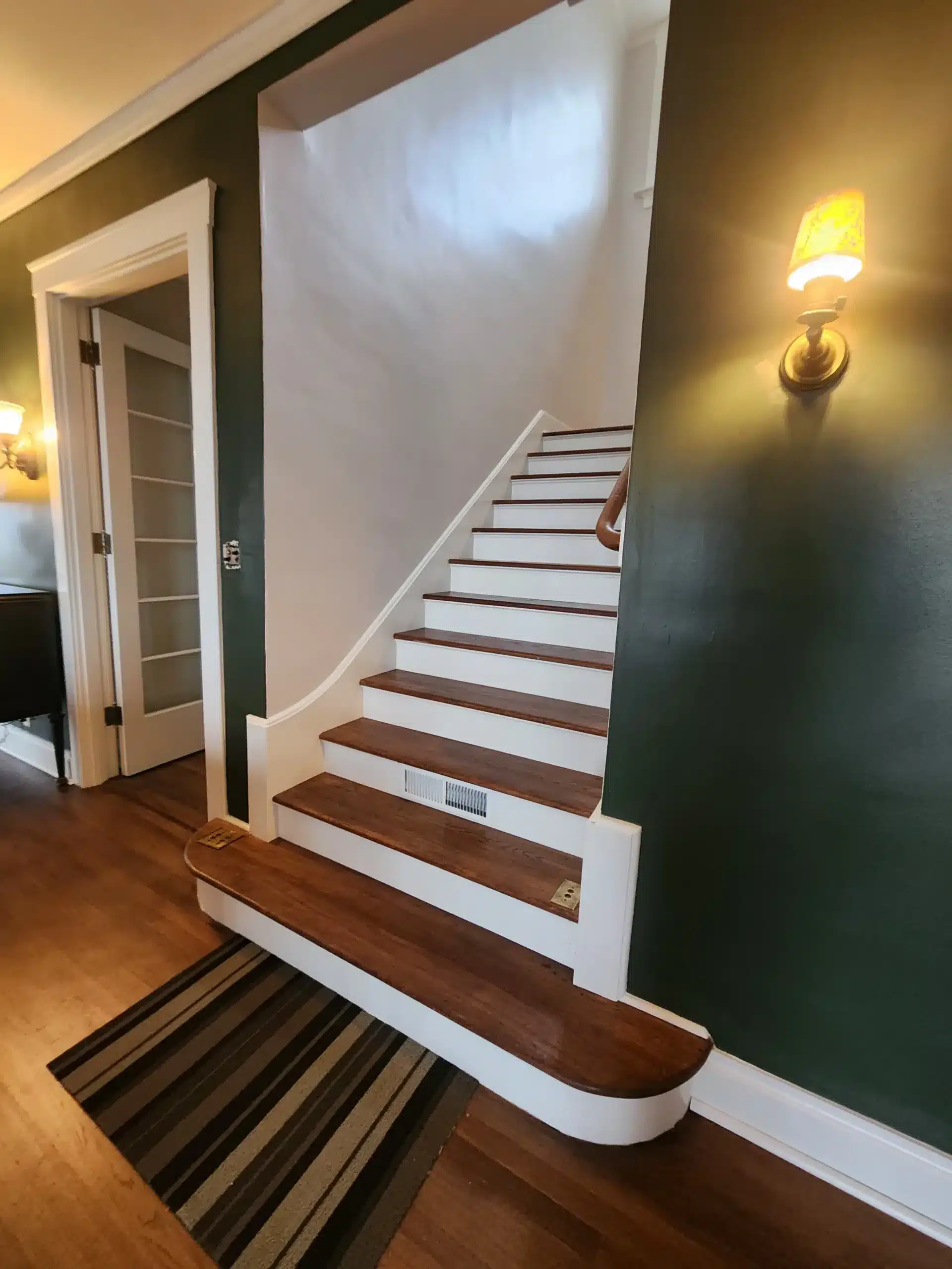 Interior residential painting Interior staircase with freshly painted dark green walls, white risers, and stained wood treads