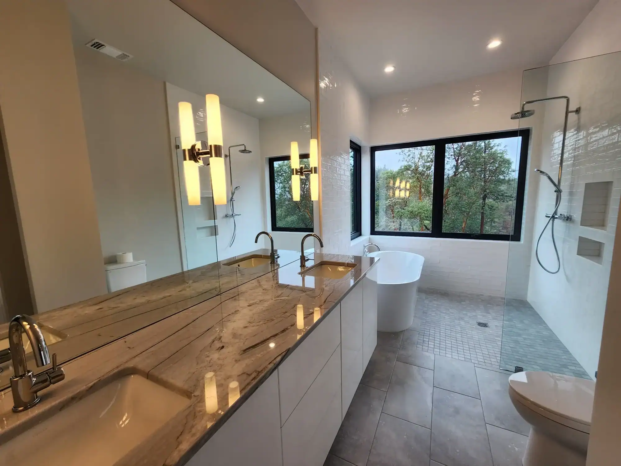 Interior residential painting Luxury primary bathroom with painted white walls, marble countertops, freestanding tub, and walk-in glass shower