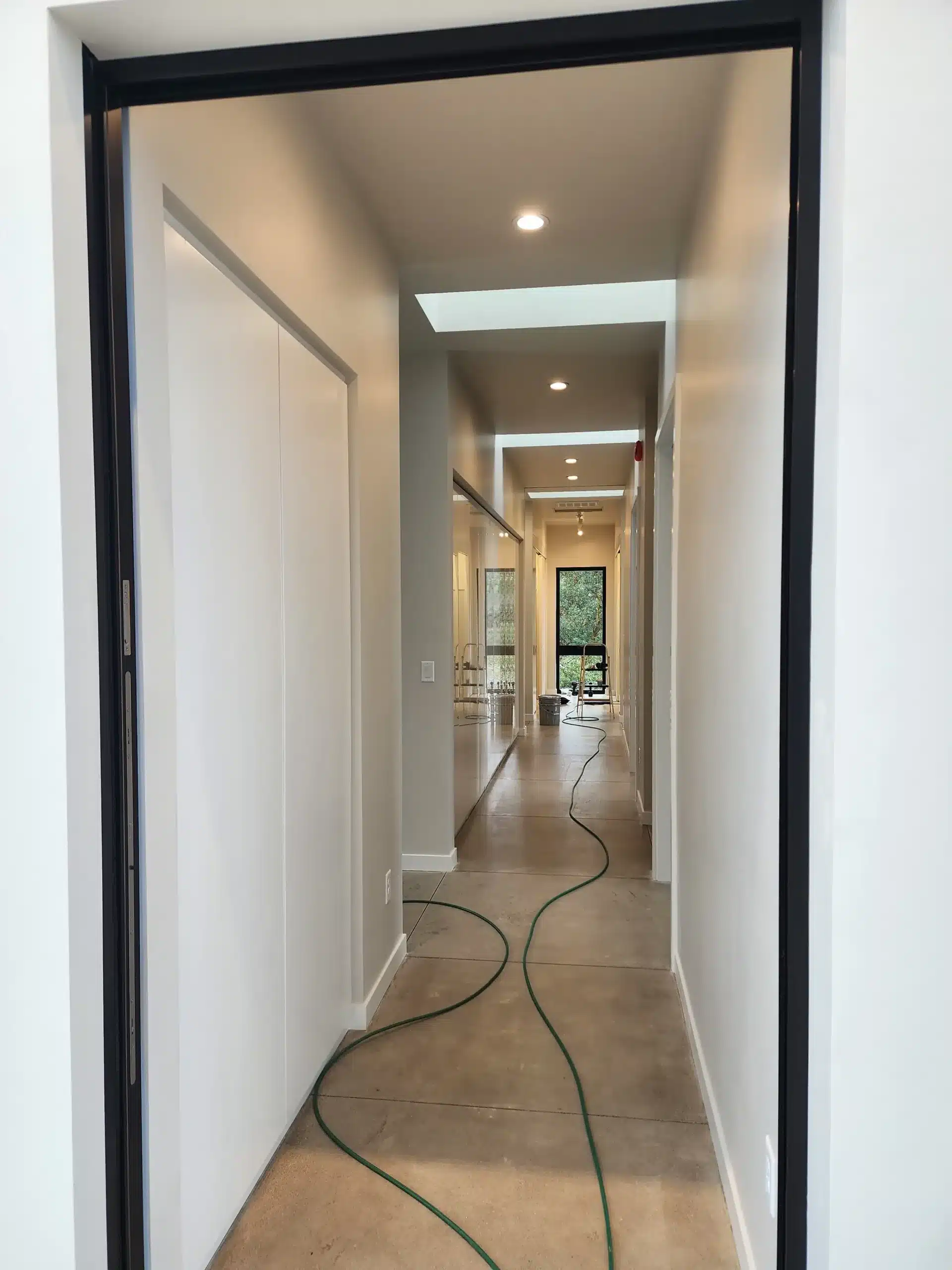 Interior residential painting Freshly painted white hallway in a modern new construction home with skylights and polished concrete floors