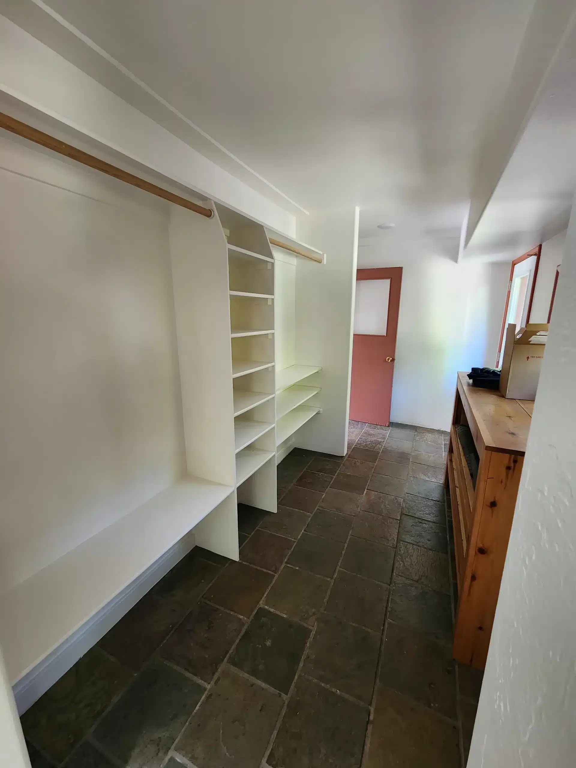 Cabinet Painting Walk-in closet with freshly painted white built-in shelving over dark slate tile flooring