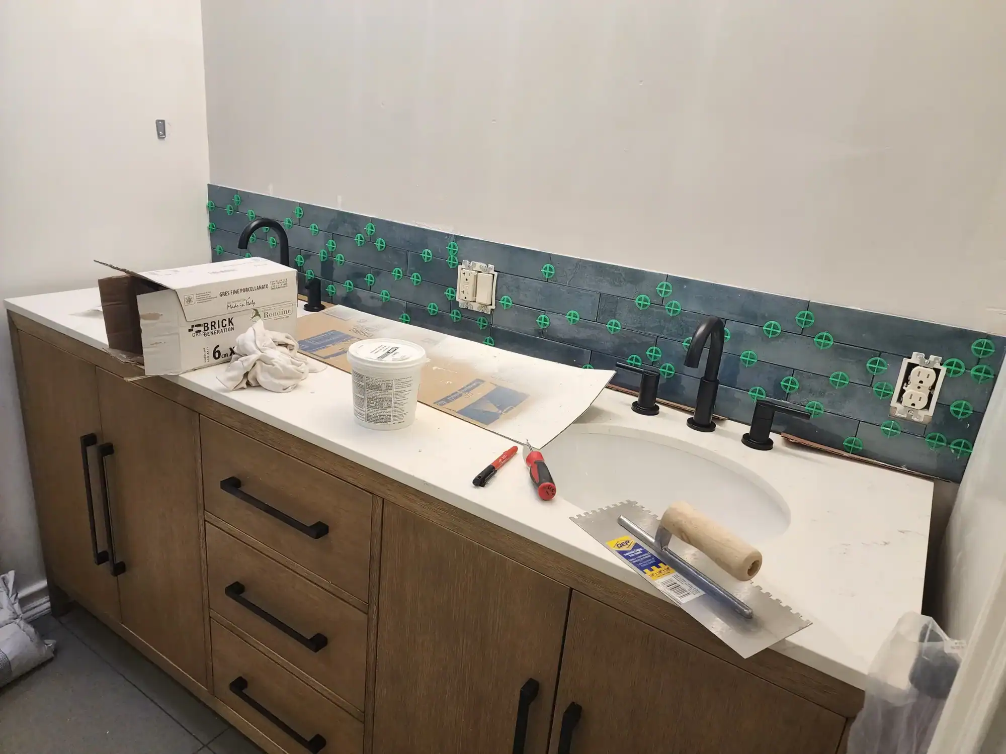 Cabinet Painting Bathroom vanity mid-renovation with blue subway tile backsplash set with green spacers and trowel on the counter
