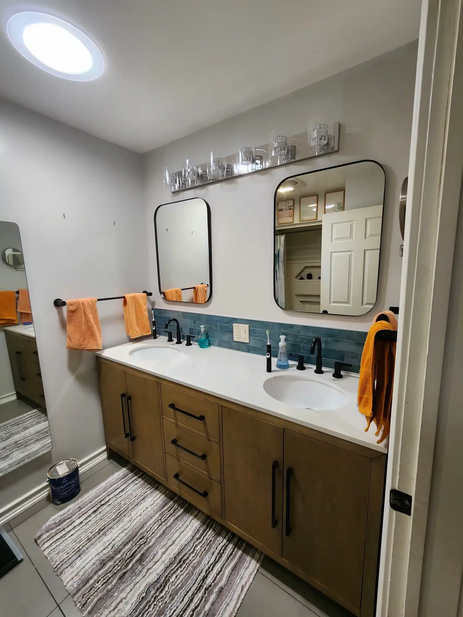 Cabinet Painting Freshly painted bathroom with double vanity, gray walls, and blue tile backsplash