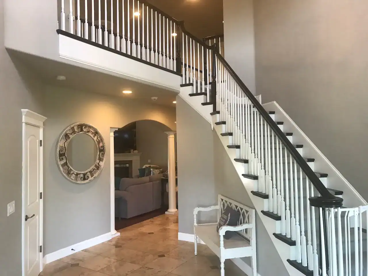 6CBA0864-FED8-4F9A-89F7-440FCBB7B96D Two-story foyer with freshly painted gray walls, white balusters, and dark-stained stair treads and handrail