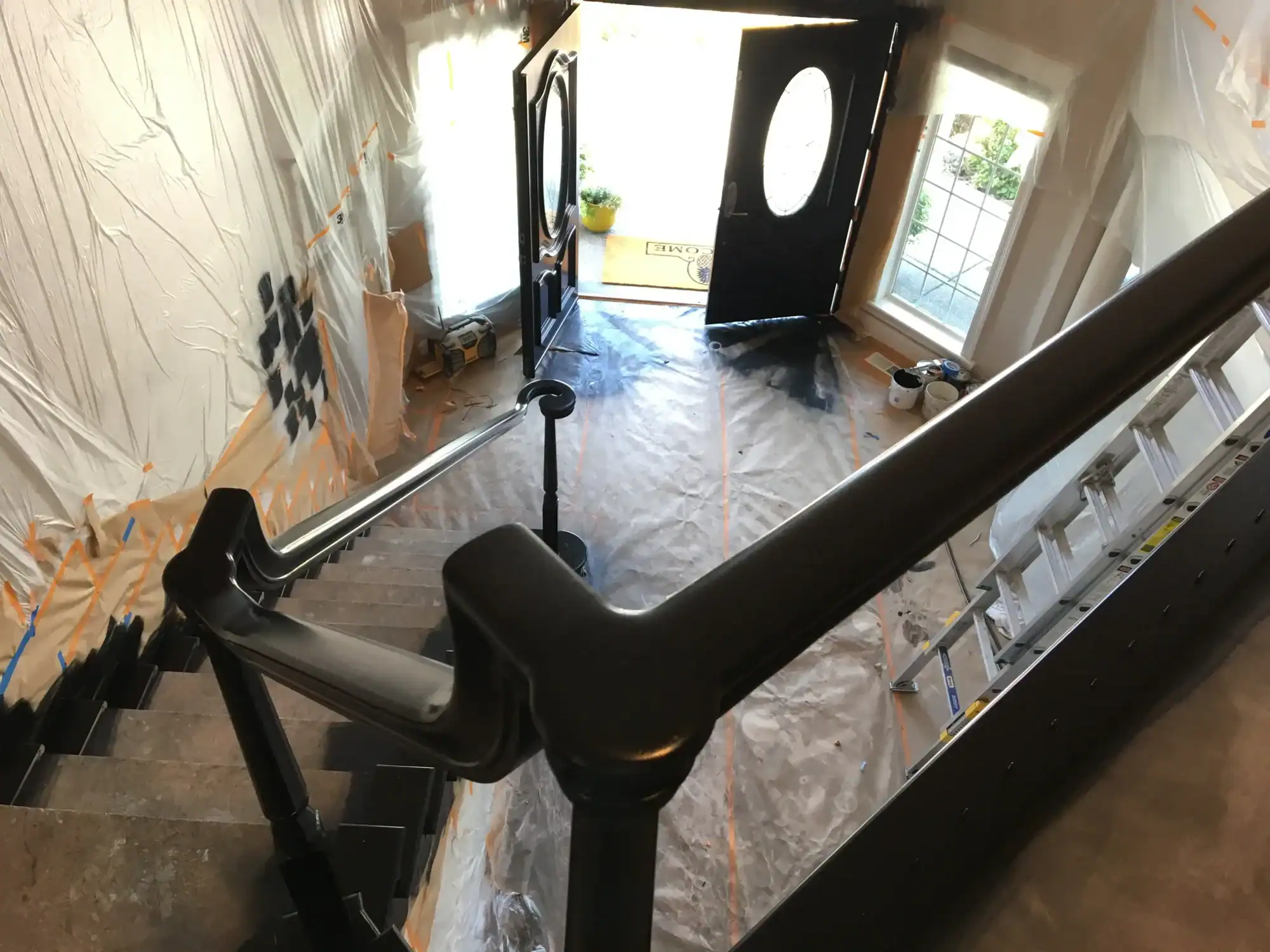 Interior residential painting Interior staircase with freshly painted black iron railings, walls and floors protected with plastic sheeting mid-project