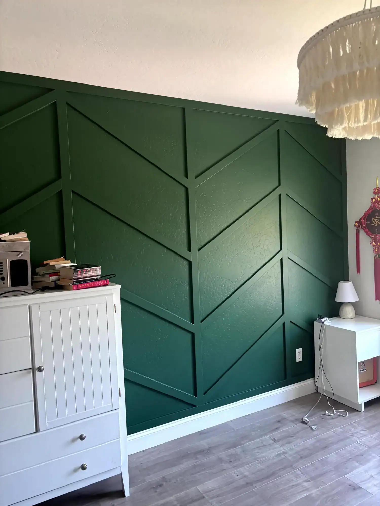 Interior residential painting Forest green chevron board and batten accent wall in a bedroom with white furniture and gray plank flooring
