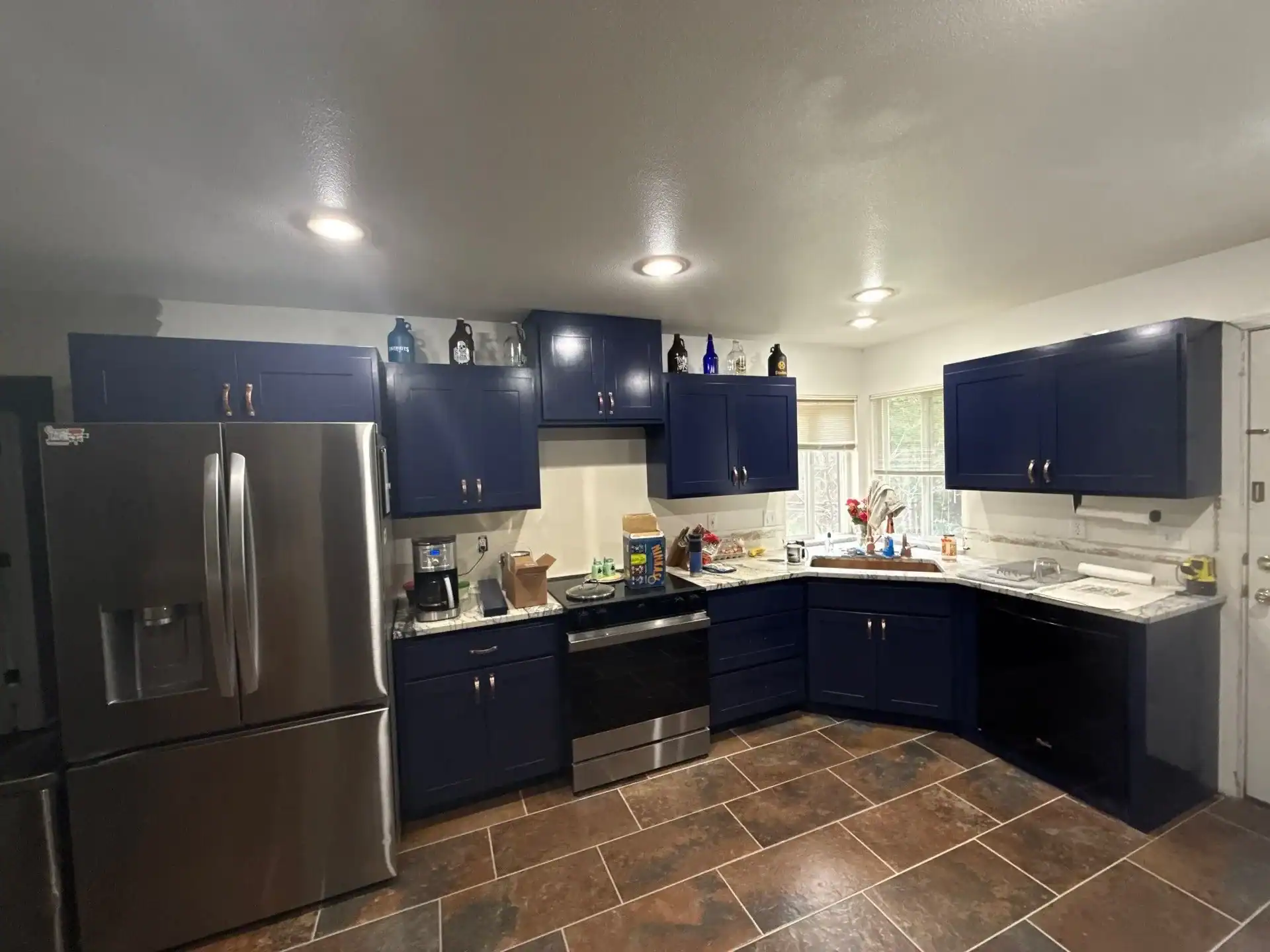 down-net_http20260223-399-xiqfrf Kitchen cabinets refinished in navy blue with stainless steel appliances and marble-look countertops