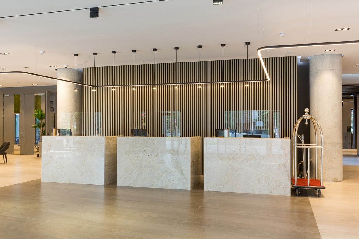 Interior of a hotel lobby with reception desks with transparent coronavirus plexiglass lexan clear sneeze guards