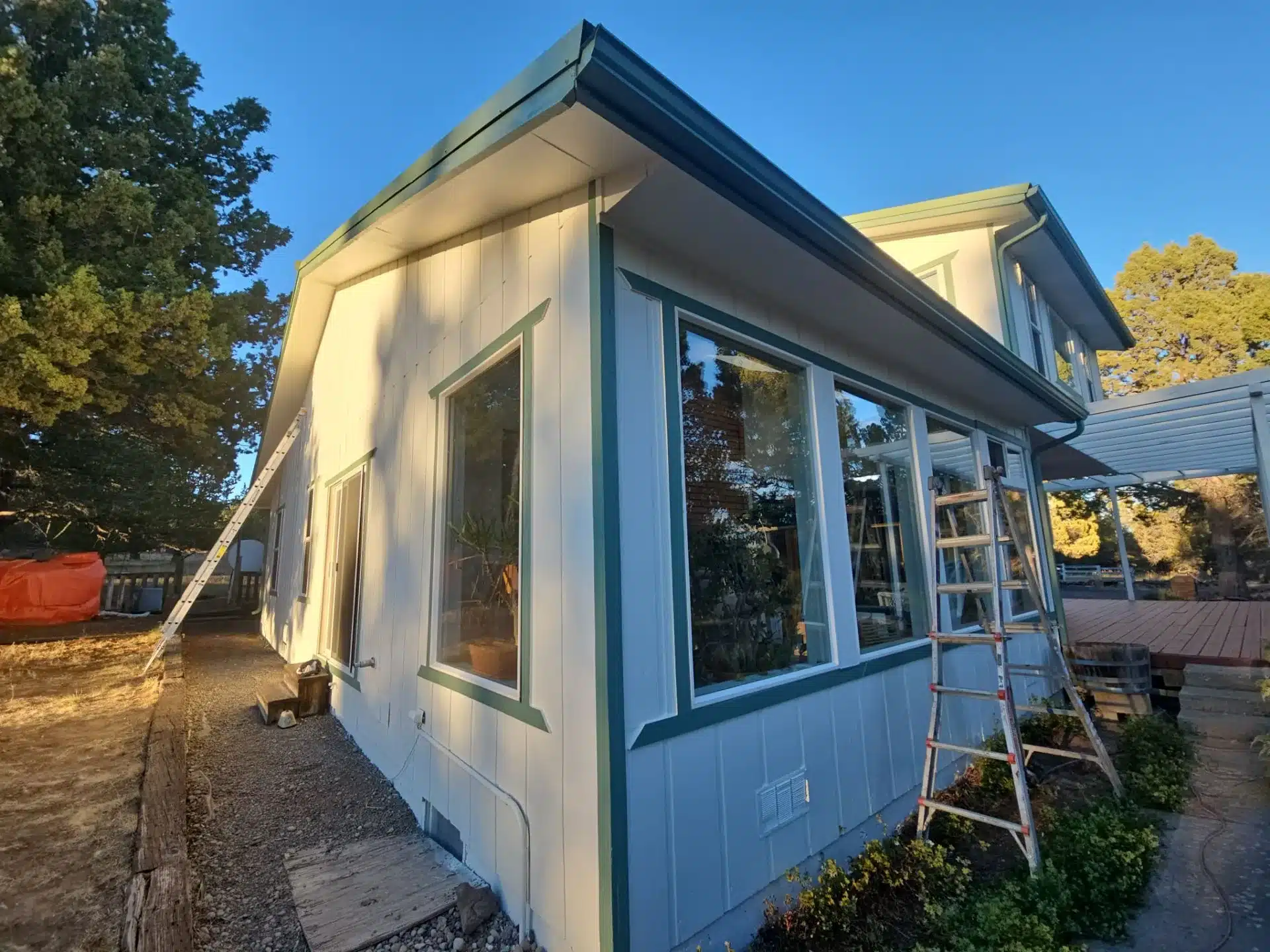 Cream and Blue Residential Exterior Cream painted residential home exterior with blue-green trim, metal roof, and large windows in Medford, OR