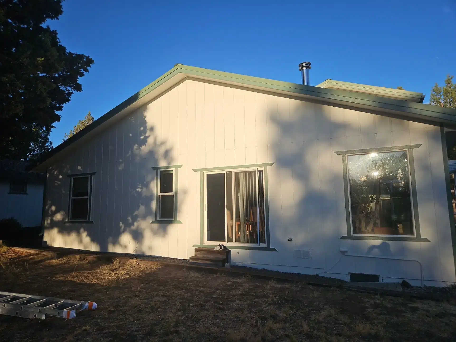 Cream Residential Home Exterior Cream painted residential home exterior with sage green trim, multiple windows, and metal roof in Medford, OR
