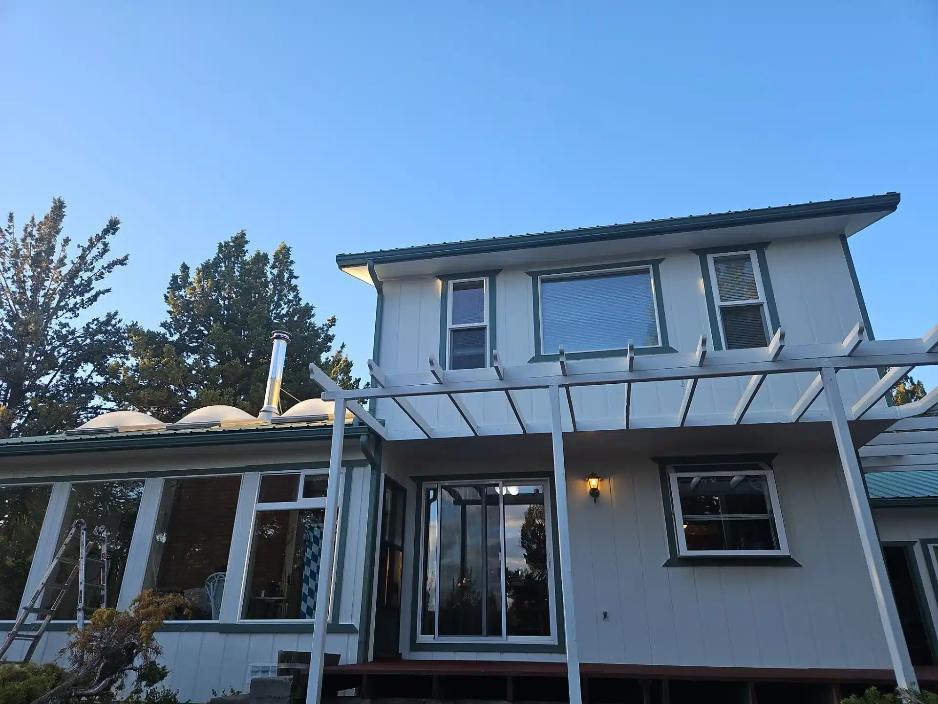 White Painted Residential Home Exterior White painted residential home exterior with dark metal roof, large windows, and metal deck railing in Medford, OR