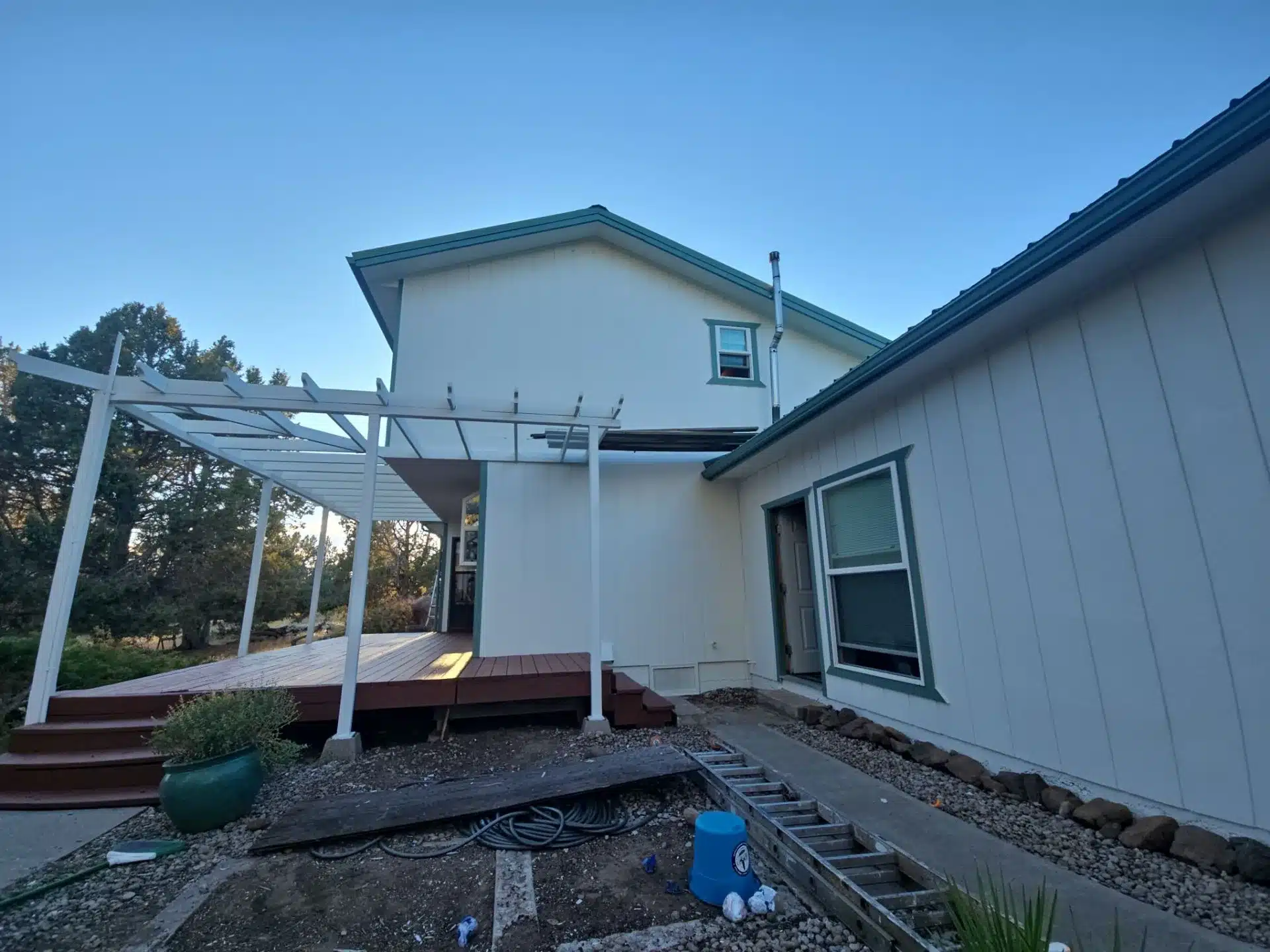 White Painted Residential Home Exterior White painted residential home exterior with teal metal roof trim, covered patio, and multiple windows in Medford, OR